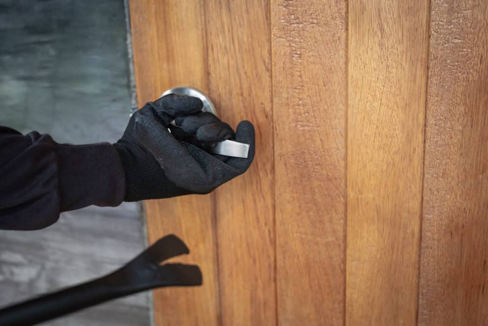Close up of someone in gloves breaking into a door