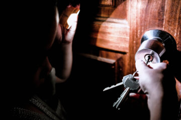 Someone opening door at night with keys in the lock.