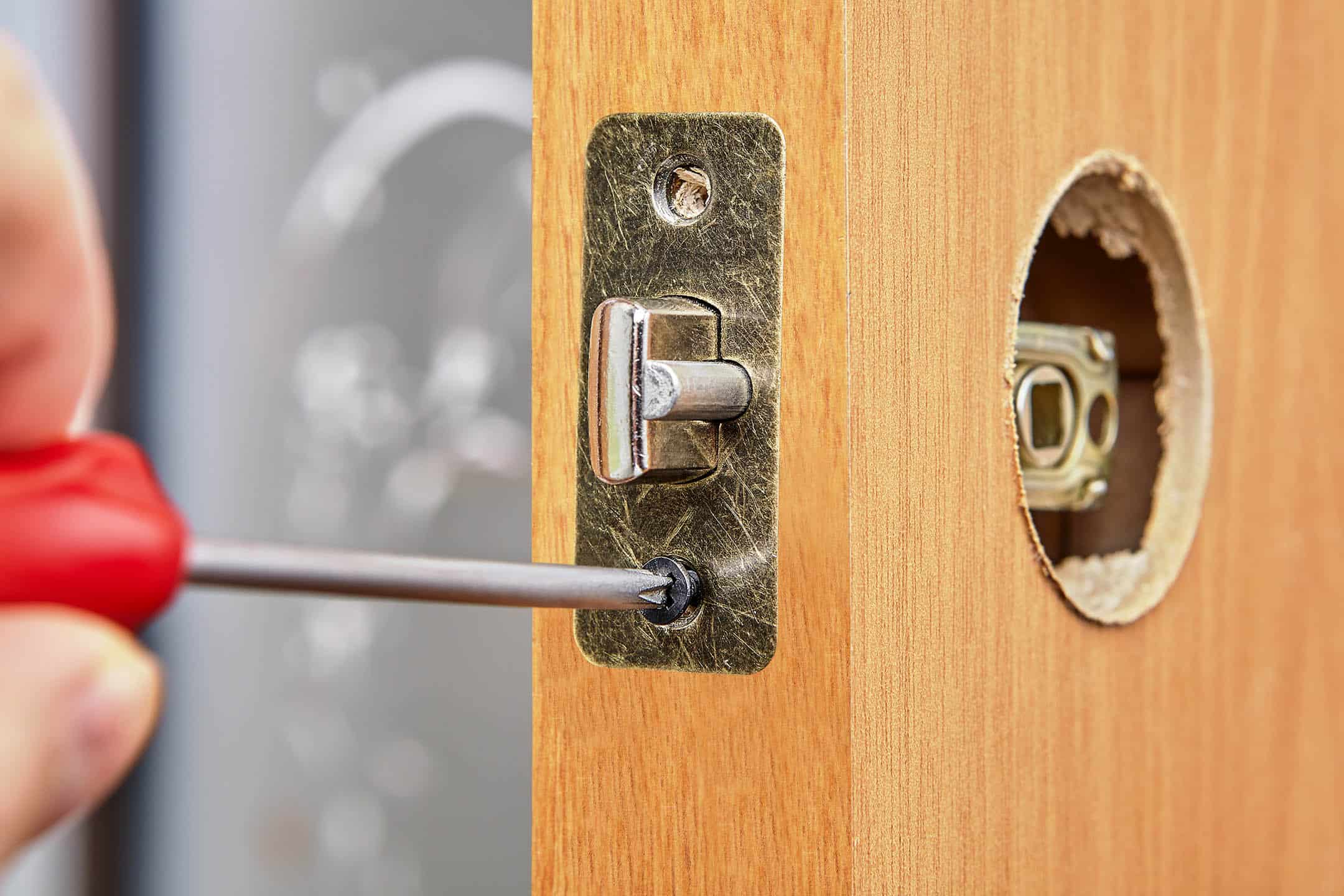 Close up of a door latch without handles being screwed signifying a door lock repair